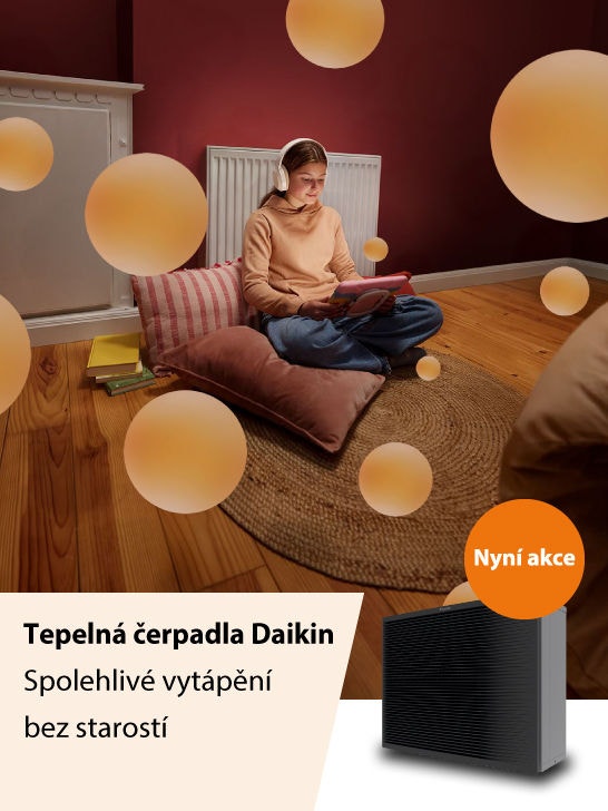 Muž se sluchátky na uších leží na pohovce a prohlíží si mobilní telefon.